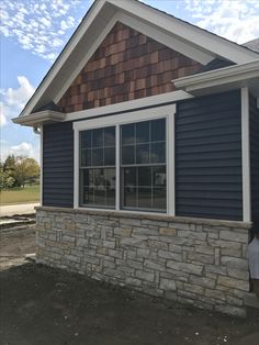 a man standing in front of a blue house with white trim on the windows and shingles