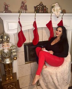 a woman sitting on a chair in front of a fireplace with stockings hanging from the mantel