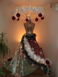 a mannequin is adorned with white feathers and christmas lights in the corner of a room