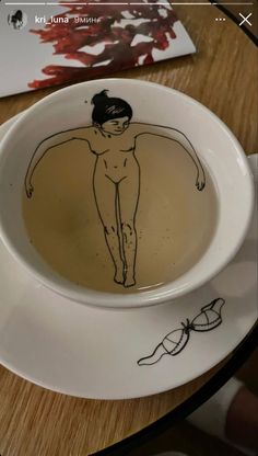 a cup with a drawing of a naked woman in it on top of a table