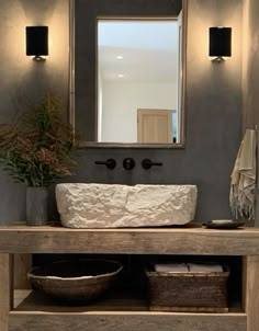 a bathroom with a sink, mirror and two baskets on the counter top in front of it