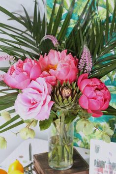 a vase filled with pink flowers sitting on top of a table next to lemons