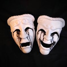 two white masks with black paint on them