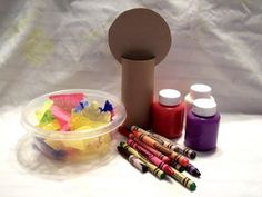 some crayons and markers are sitting next to a container with the lid open