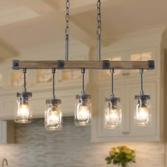 a kitchen island with mason jars hanging from it's lights and a wooden beam