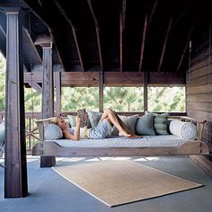 a person laying on a couch under a wooden structure with lots of pillows in front of them