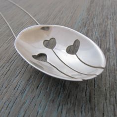 a silver spoon with hearts on it sitting on a wooden table