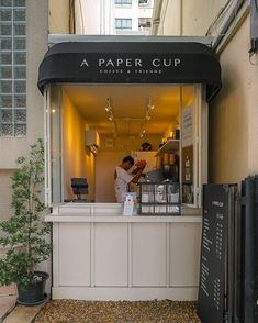 a small coffee shop on the side of a building with a man working behind it