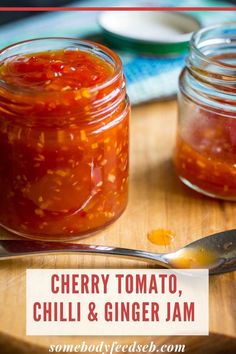 two jars of cherry tomato chili and ginger jam on a cutting board with spoons