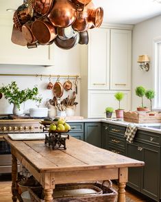 a wooden table in a kitchen with pots and pans hanging from the ceiling