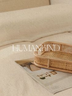 a wicker basket sitting on top of a bed next to an open book and magazine