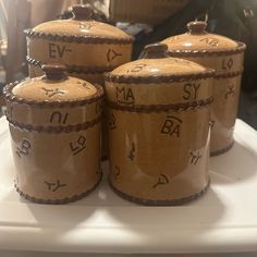 three brown jars sitting on top of a white table next to each other with writing on them