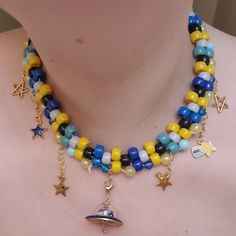 a woman wearing a multi colored beaded necklace with stars and charms on it's neck