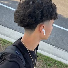 a person with short hair and ear piercings standing on the side of the road