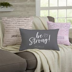 three pillows on a couch with the words be strong written in cursive font