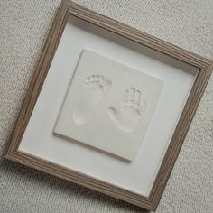 a white frame with a baby's hand and foot prints in it on the floor