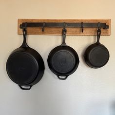 three cast iron skillets hanging on a wall