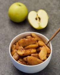 a bowl filled with sliced apples next to an apple