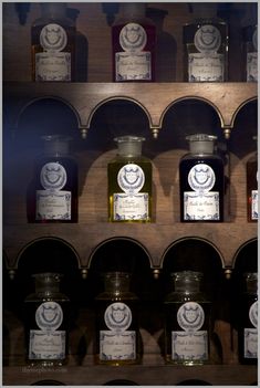 several jars with labels on them are lined up against a wooden shelf in a store