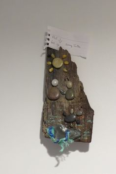 a piece of wood with rocks on it and a note pinned to the wall next to it