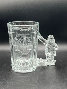 a clear glass cup with a small plastic figurine next to it