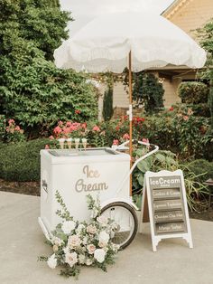 an ice cream cart is decorated with white flowers and greenery, along with a sign that says ice cream