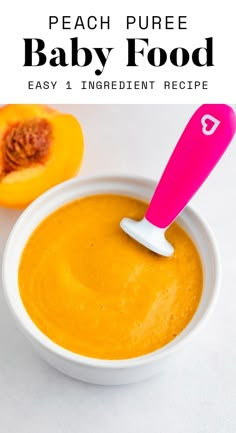 peach pure baby food in a white bowl with a pink spatula sticking out of it