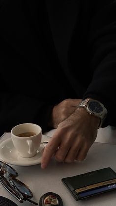 a person sitting at a table with a cup of coffee and other items on it