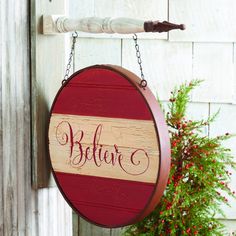 a wooden sign hanging from the side of a building next to a potted plant