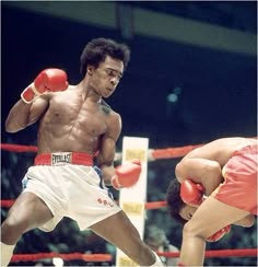 two men in boxing stances on the ring during a match, one is wearing red gloves