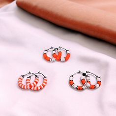 Show your team spirit and represent your game day team colors with these stunning orange and white heishi bead stainless steel hoop earrings.  - Available in 3 sizes: 1", 1.5" and 1.75" - Three unique designs to choose from Make a statement and cheer on your team in style with these trendy earrings. Perfect for game day or any occasion. Grab a pair now and show your support! Beaufort Nc, Spirit Game, Bead Hoop Earrings, Team Mom, Clay Bead, Trendy Earrings, Heishi Beads, Beaded Hoop Earrings, Beaded Hoops