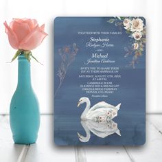 a blue vase with a pink rose in it next to a wedding card