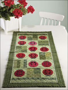 a green table runner with red ladybugs on it next to a white chair