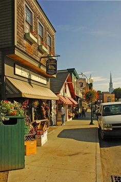 a truck parked on the side of a road next to buildings and shops with people walking by