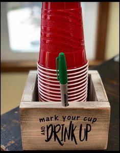 a stack of red cups sitting inside of a wooden box on top of a table