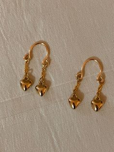 three pairs of gold earrings on a white surface