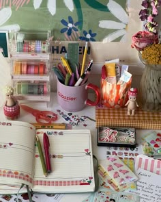 an open notebook sitting on top of a table filled with lots of crafting supplies