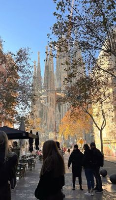 people are walking down the street in front of tall buildings with spires on them