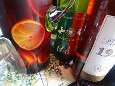 several bottles of wine and glasses on a table with grapes, oranges, and other items