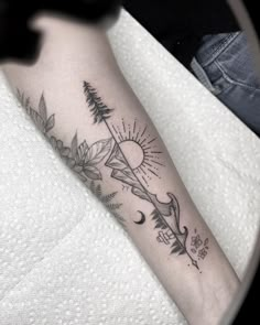 a person with a tattoo on their arm that has trees and sun in the background