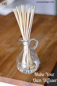 a glass vase filled with reeds on top of a wooden table