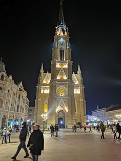 people are walking around in front of a church at night