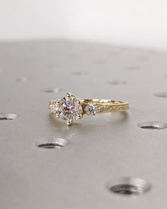 a diamond ring sitting on top of a silver surface with holes in the floor behind it