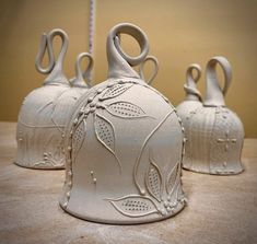 three white vases sitting on top of a table next to each other with designs