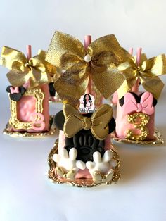 three minnie mouse candle holders with bows on them, one is pink and the other is gold