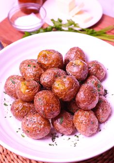 a white plate topped with meatballs covered in seasoning next to other food items