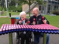 an elderly man in a wheel chair playing with musical instruments