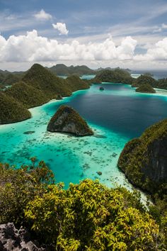 an aerial view of several small islands in the ocean with blue water and green vegetation