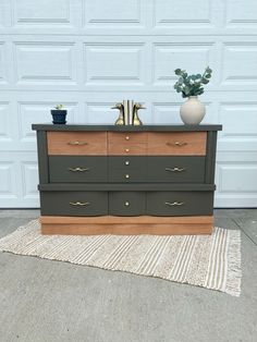 a dresser with two vases sitting on top of it next to a garage door