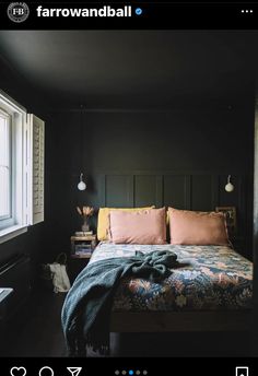 a bed with two pillows and blankets on it in a dark room next to a window